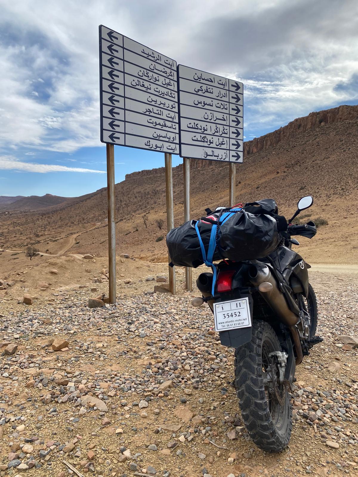 Reisemotorrad an einer Wegmarkierung in karger Landschaft